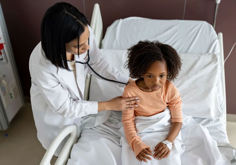 little girl being examined by doctor in hospital bed