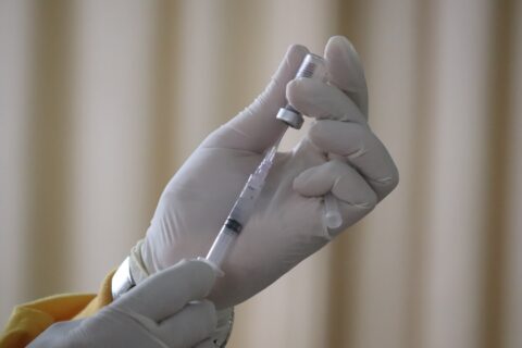 person withdrawing flu vaccine from vial